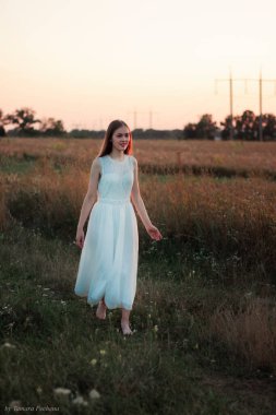 Güzel bir kız gün batımında beyaz bir elbiseyle bir tarlada dans ediyor. Mutlu kadın. Kavram. Gelin