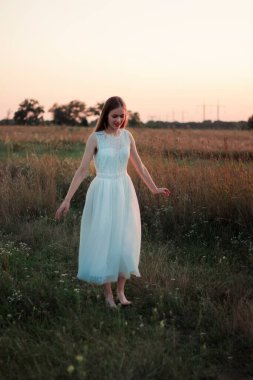 Güzel bir kız gün batımında beyaz bir elbiseyle bir tarlada dans ediyor. Mutlu kadın. Kavram. Gelin