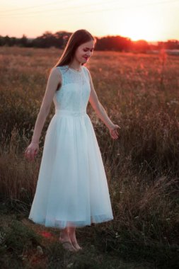 Güzel bir kız gün batımında beyaz bir elbiseyle bir tarlada dans ediyor. Mutlu kadın. Kavram. Gelin