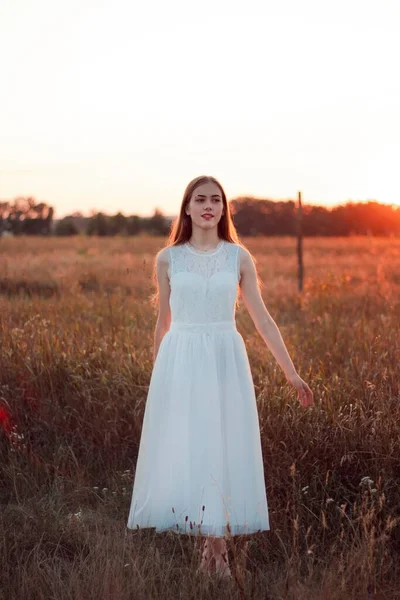 Güzel bir kız gün batımında beyaz bir elbiseyle bir tarlada dans ediyor. Mutlu kadın. Kavram. Gelin