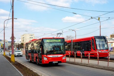 BRATISLAVA, SLOVAKIA - MARCH 07, 2022. Bus Iveco Urbanway 10,5M #2410 and tram Skoda 30T2 #7528 riding with passengers in the streets of Bratislava.