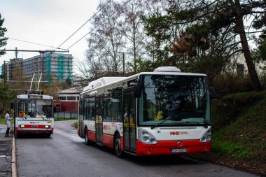 BANSKA BYSTRICA, SLOVAKIA - Nisan 09, 2022. Irisbus Citelis 12 ve Tramvay Skoda 14Tr # 1001 otobüsleri Banska Bystrica sokaklarında yolcularla yolculuk ediyor..