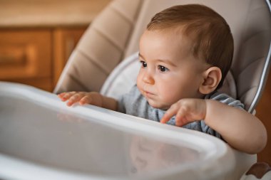 Sevimli bebek sandalyede oturuyor. Bebeklerin ilk beslenmesi konsepti