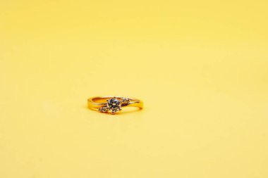 Solitaire nişan yüzüğü sarı arka planda.