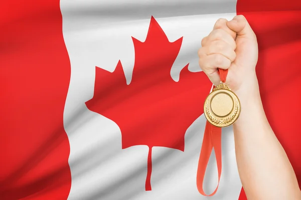 Medaille in der hand mit Flagge auf Hintergrund - Kanada — Stockfoto