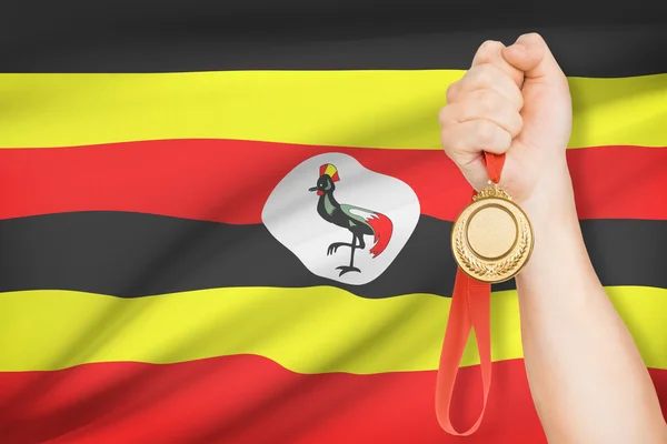 Medaille in der hand mit Flagge auf Hintergrund - Republik uganda — Stockfoto