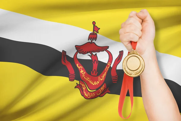 Medal in hand with flag on background - Nation of Brunei, Abode of Peace — Stock Photo, Image