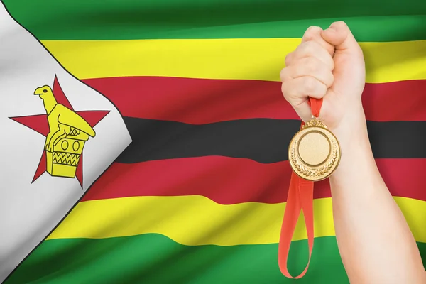 Medal in hand with flag on background - Republic of Zimbabwe — Stock Photo, Image