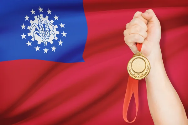 Medal in hand with flag on background - Republic of the Union of Myanmar — Stock Photo, Image