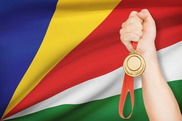 Medaille in der hand mit Flagge auf Hintergrund - Seychellen — Stockfoto