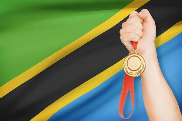 Medalj i hand med flaggan i bakgrunden - Förenade republiken tanzania — Stockfoto