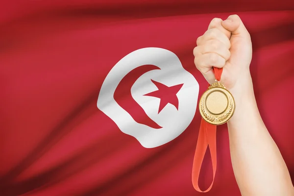 Medalj i hand med flaggan i bakgrunden - tunisiska Republiken — Stockfoto