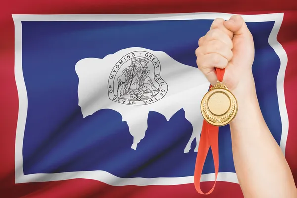 Medal in hand with flag on background - State of Wyoming. Part of a series. — Stock Photo, Image