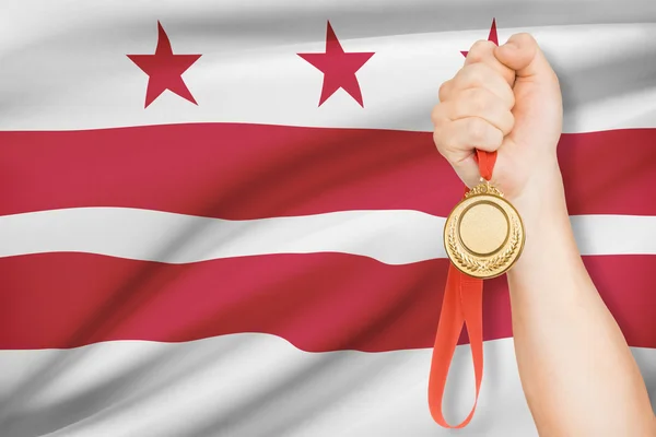Medaille in der hand mit Flagge auf Hintergrund - District Of Columbia. Teil einer Serie. — Stockfoto