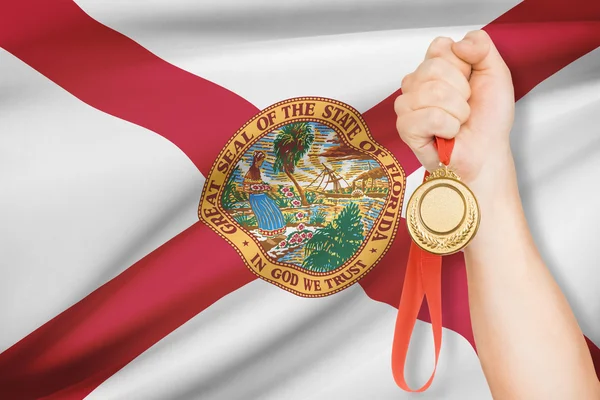 Medaille in der hand mit Flagge auf Hintergrund - Bundesstaat Florida. Teil einer Serie. — Stockfoto