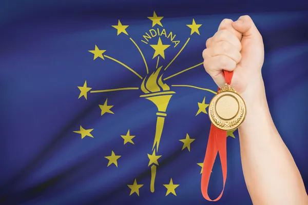 Medalj i hand med flaggan i bakgrunden - delstaten indiana. del av en serie. — Stockfoto