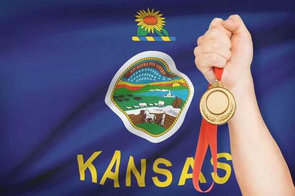 Medal in hand with flag on background - State of Kansas. Part of a series. — Stock Photo, Image