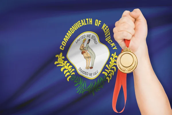 Medalj i hand med flaggan i bakgrunden - commonwealth av kentucky. del av en serie. — Stockfoto