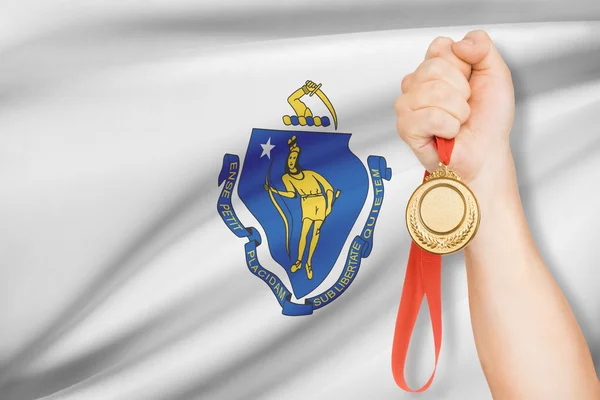 Medal in hand with flag on background - Commonwealth of Massachusetts. Part of a series. — Stock Photo, Image