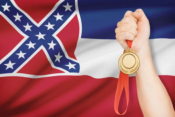 Medaille in der hand mit Flagge auf Hintergrund - Staat Mississippi. Teil einer Serie. — Stockfoto