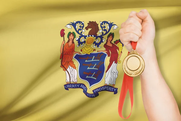 Medal in hand with flag on background - State of New Jersey. Part of a series. — Stock Photo, Image