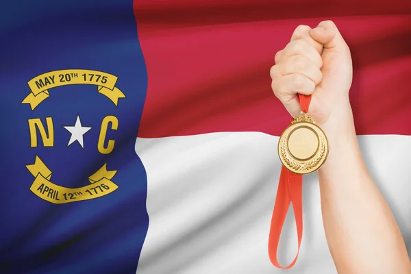 Medaille in der hand mit Flagge auf Hintergrund - Bundesstaat North Carolina. Teil einer Serie. — Stockfoto