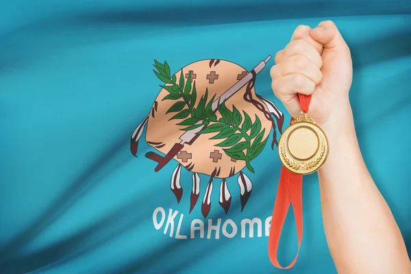 Medaille in de hand met vlag op achtergrond - staat oklahoma. bij een reeks hoort. — Stockfoto