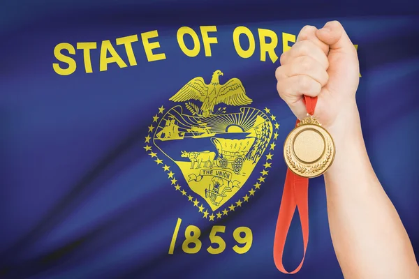 Medaglia in mano con bandiera sullo sfondo - stato dell'oregon. parte di una serie. — Foto Stock