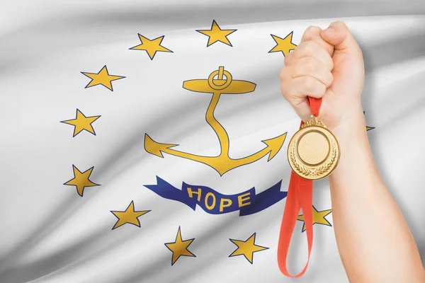 Medaille in der hand mit Flagge auf Hintergrund - Bundesstaat Rhode Island und Vorsehung-Plantagen. Teil einer Serie. — Stockfoto