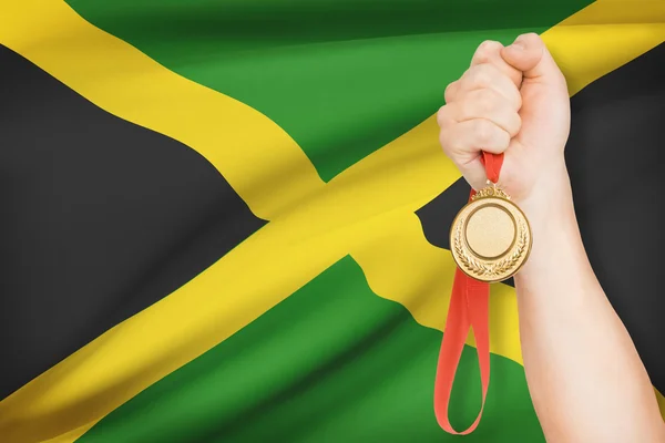 Medalj i hand med flaggan i bakgrunden - jamaica — Stockfoto