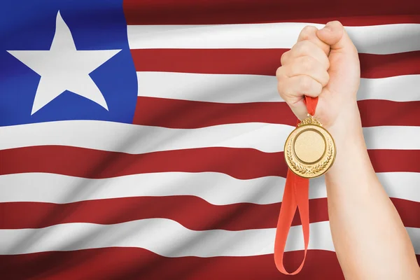 Medaille in der hand mit Flagge auf Hintergrund - Republik liberia — Stockfoto