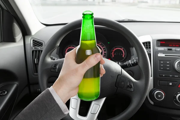 Mannelijke bedrijf flesje bier tijdens het rijden auto — Stockfoto