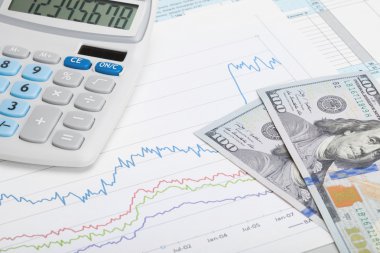 100 dolarlık banknot ve hesap makinesi hisse senedi grafiği