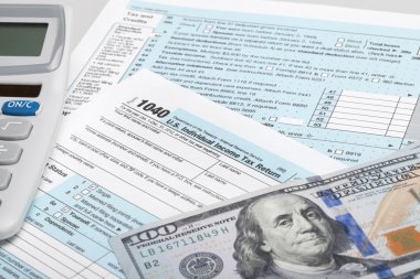 hesap makinesi ve 100 ABD Doları faturaları ile ABD vergi form 1040