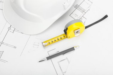 Beyaz inşaat kask plan üstünde kalem ve ölçü bandı ile