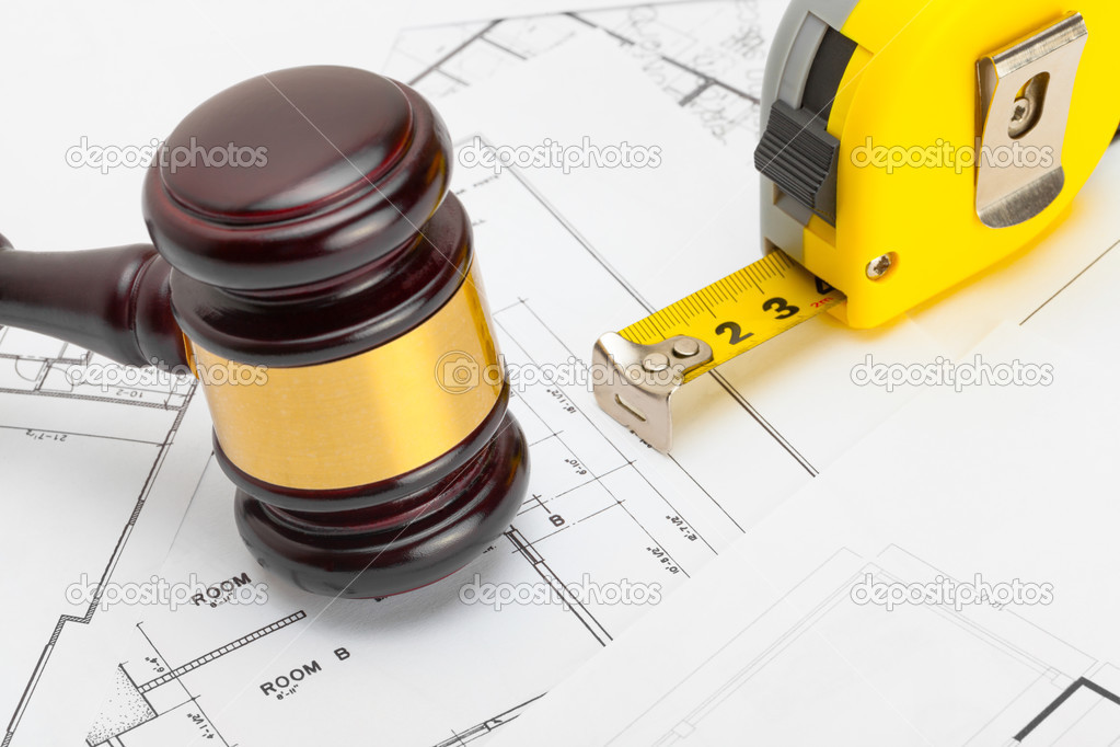 Wooden judge gavel with measure tape above construction blueprint - studio shoot