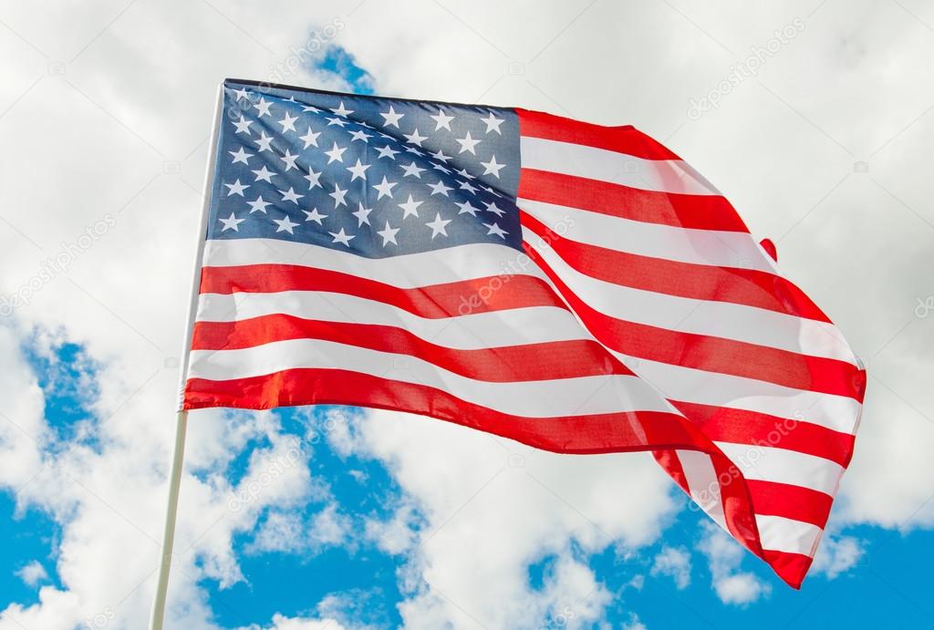 USA flag waving in the wind with white clouds on background - outdoors shoot