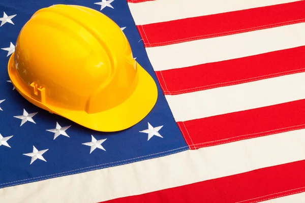 Construction helmet laying over USA flag - studio shoot — Stock Photo, Image