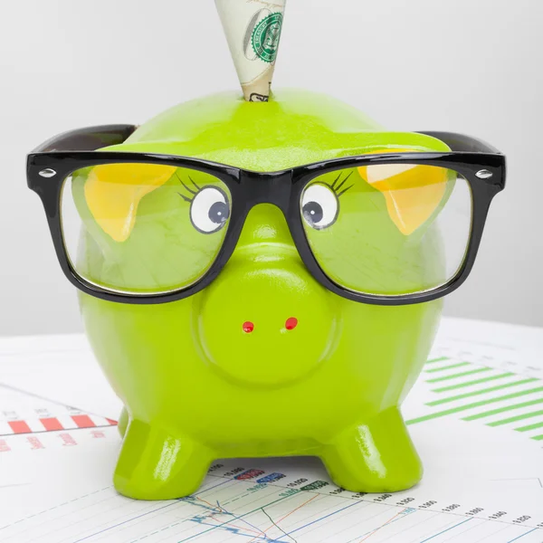 Green piggy bank over stock market chart with 100 dollars banknote - 1 to 1 ratio — Stock Photo, Image