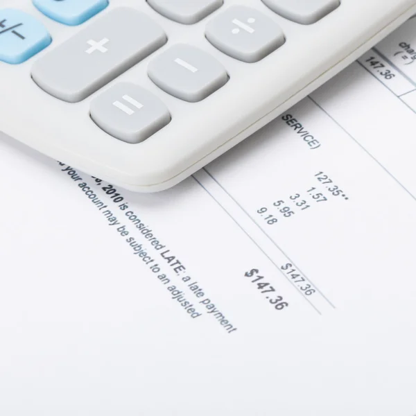 Calculator over utility bill under it - 1 to 1 ratio — Stock Photo, Image