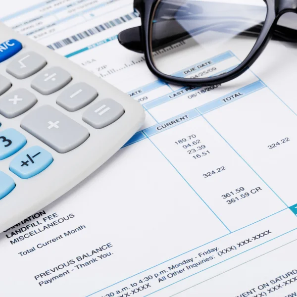 Studio shot of calculator and glasses over some receipt — Stock Photo, Image