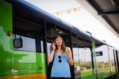 Genç atletik kadın tren istasyonunda tren yakınında müzik dinliyor..