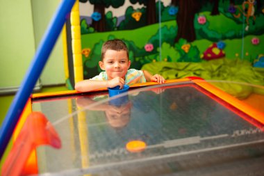 Little child boy playing air hockey in the play center
