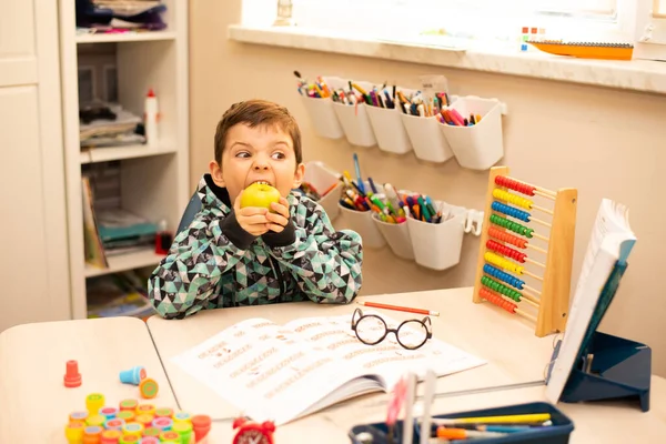 Little Schoolboy Sits His Desk Greedily Bites Yellow Apple — Stockfoto