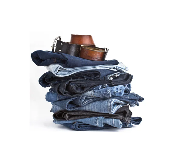 Jeans trousers stack with leather belts — Stock Photo, Image