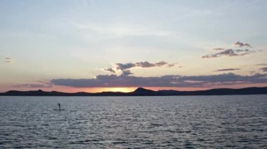 Gün batımında yatağın üzerinde yüzen genç bir kadının robot resmi..