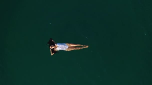 Воздушные снимки молодой женщины с длинными волосами, лежащей в воде. — стоковое видео