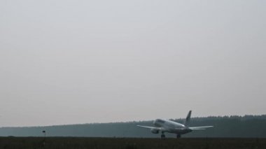 Krasnoyarsk, Rusya - 8 Ağustos 2019: Beyaz bir yolcu uçağı gün batımında havalanıyor. 4K