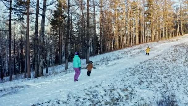 Matka a dva synové běží po stezce v zimním lese. — Stock video