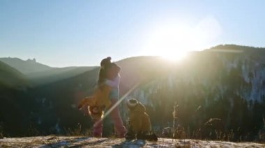 Bir anne gün batımında oğullarıyla bir dağın tepesinde eğleniyor..